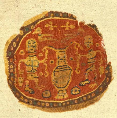 Polychrome tapestry roundel with two male figures flanking an amphora
