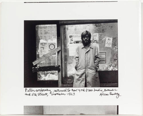 Peter Orlovsky on Bowery, NYC, standing in front of Russian Film Festival poster(s)