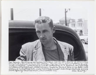 Neal Cassady at North Beach used car lot, San Francisco, (frontal image/looking down and left)