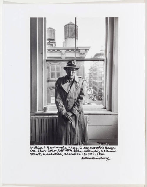William Burroughs, wearing raincoat and hat, by window in Soho, NYC