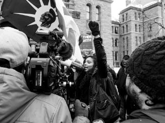 The Sum of All Parts: 1. Yusra Khogali, fist raised in front of Queen’s Park after a two week encampment at Toronto Police headquarters.